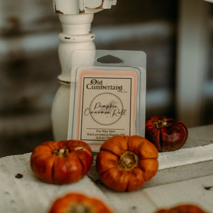 Wax melt packaging with pumpkins and a candle on a rustic surface